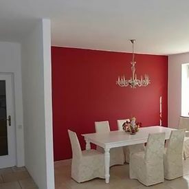 Weiße Esszimmermöbel vor roter Wand nach Malerarbeiten in Graz